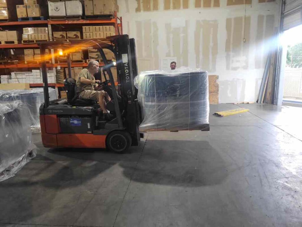 Forklift moving strapped drum pallet inside Tampa warehouse during transload