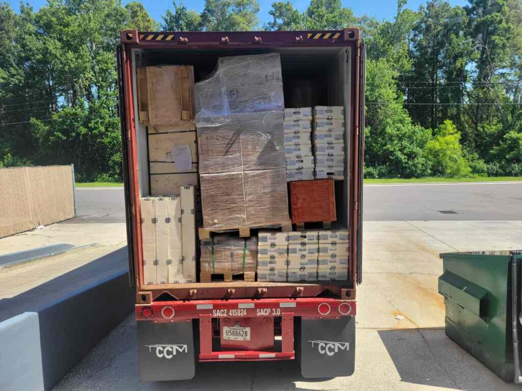 Open 40-foot container showing mixed cartons and crates before drayage transload