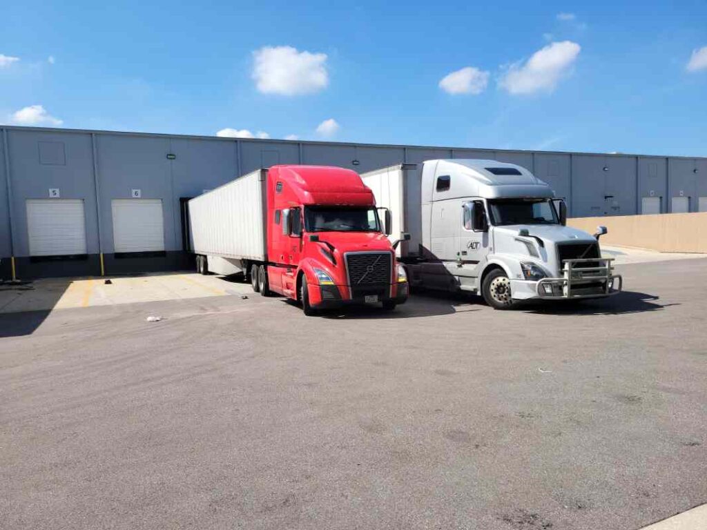 Two trucks staged at Tampa warehouse dock during multi-load cross-dock for broker